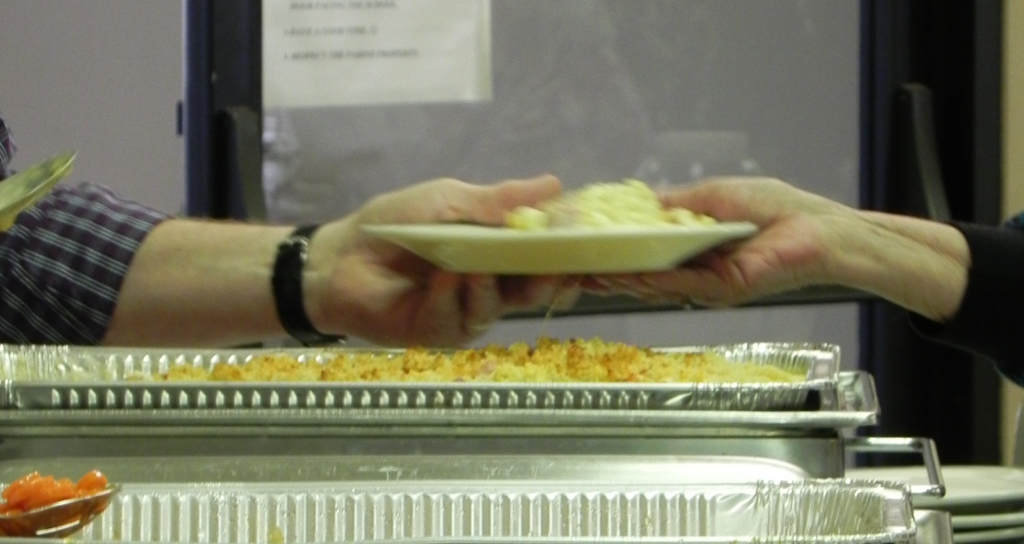 A volunteer serving a woman a plate of hearty food